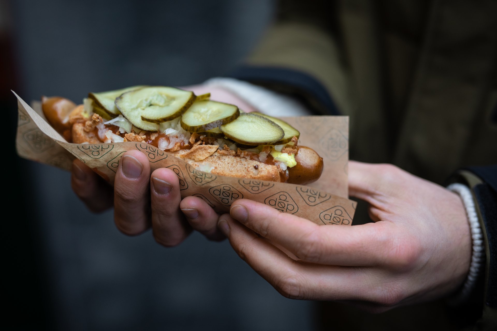 Person holder en økologisk hotdog i hånden