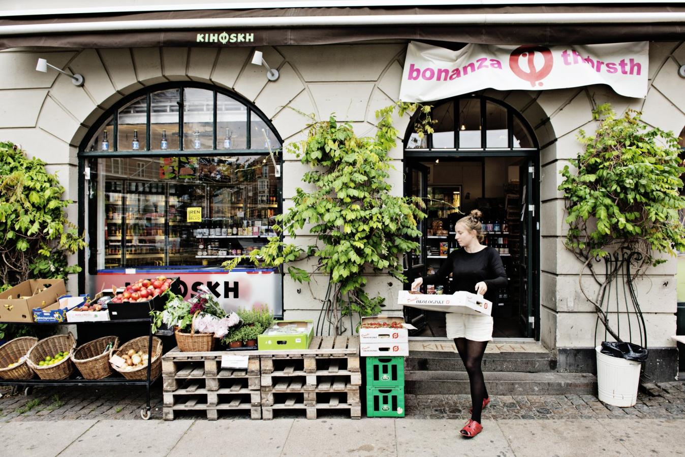 Kvinde med papkasse i hænderne på vej ud af butik på Vesterbro i København