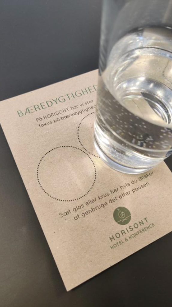 Foto af et glas der står på et papir, der lægger op til at mang bruger glasset igen